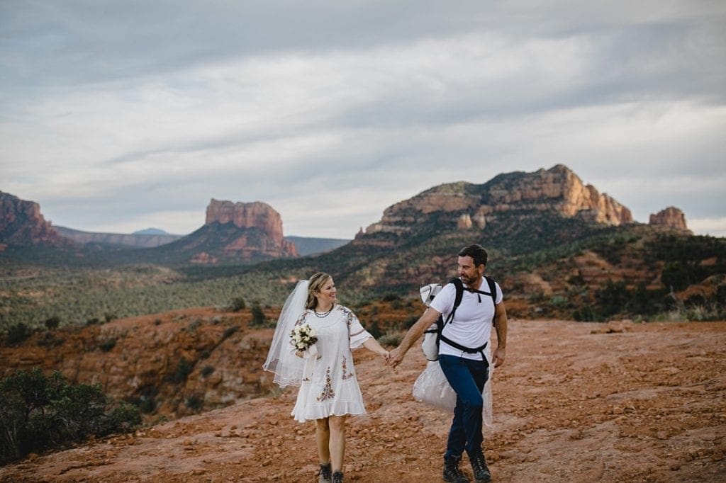 Bride and groom in hiking boots hike cathedral rock to spot for elopement in Sedona