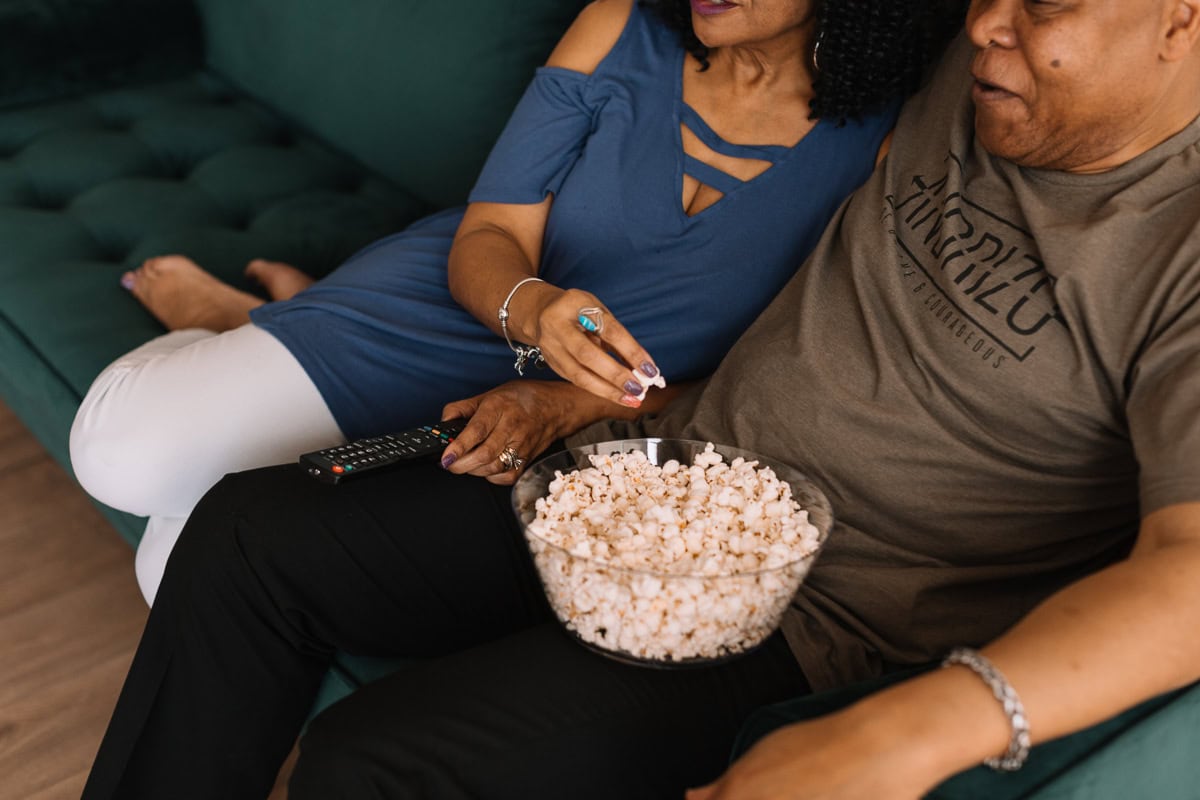 A couple watching a movie on the couch for date night in.