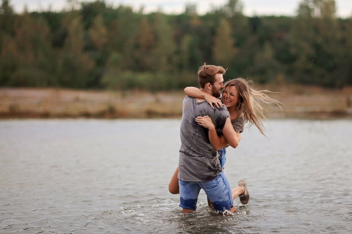 Man swinging women around in the water lovingly.