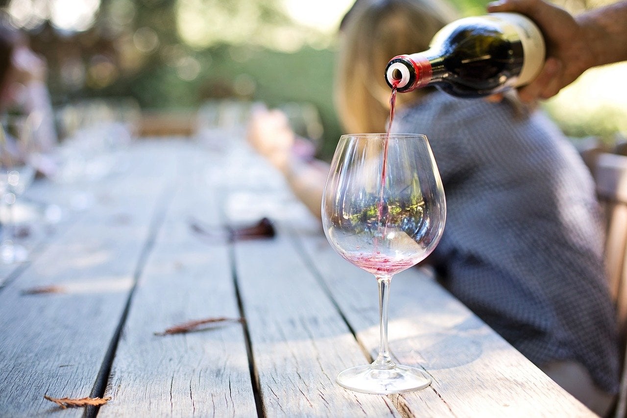 vino rosso versato in un calice in una tavola all'aperto