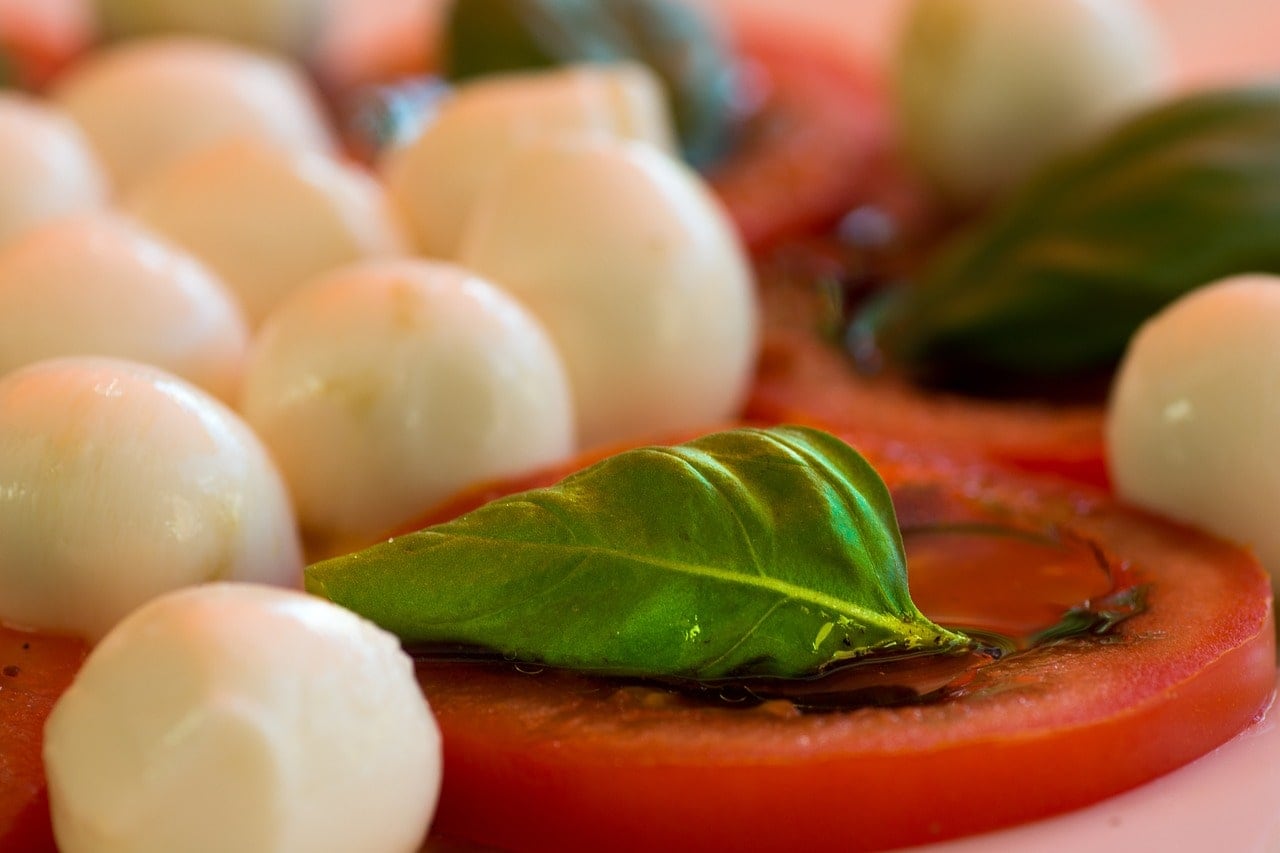 bocconcini di mozzarella di bufala su fetta di pomodoro con foglia di basilico