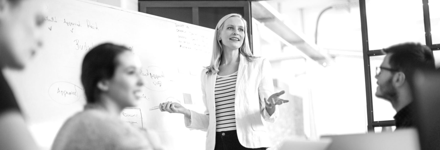 Businesswoman giving presentation on future plans to colleagues Szkolenie SPIN Selling, czyli skuteczna sprzedaż metodą SPIN