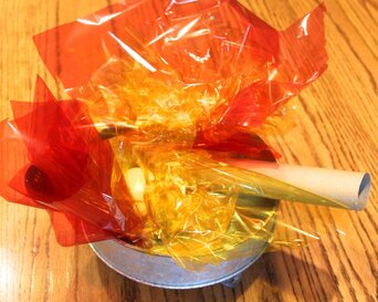 Photo of a pretend campfire in a fall dramatic play center. The fire is made with red, yellow and orange cellophane with paper towel tubes for logs.