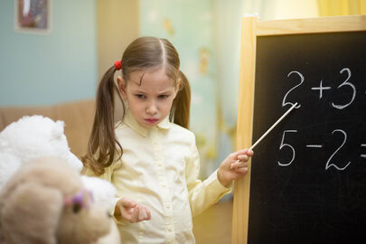 Photo of a young girl pretending to teach her stuffed animals how to add.