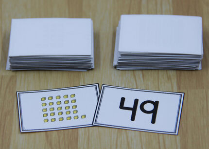 Photo of two place value war cards - one showing the numeral 49 and the other showing 26 "ones" cubes.