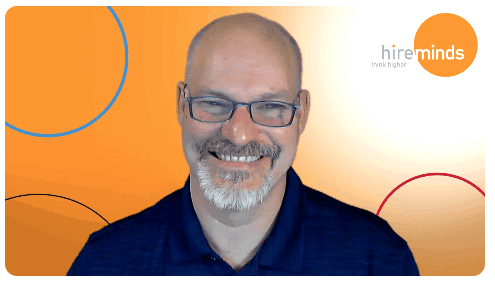 A person wearing glasses and smiling at the camera
Description automatically generated