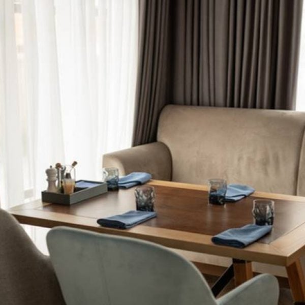 served wooden table surrounded by cozy soft velvet sofa armchars by window with white chiffon curtains 274679 2395