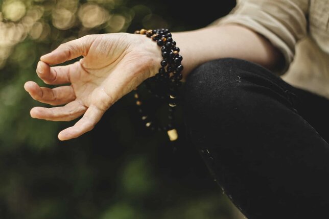 hindu mantras for manifestation close up of persons hand while meditating with mala beads