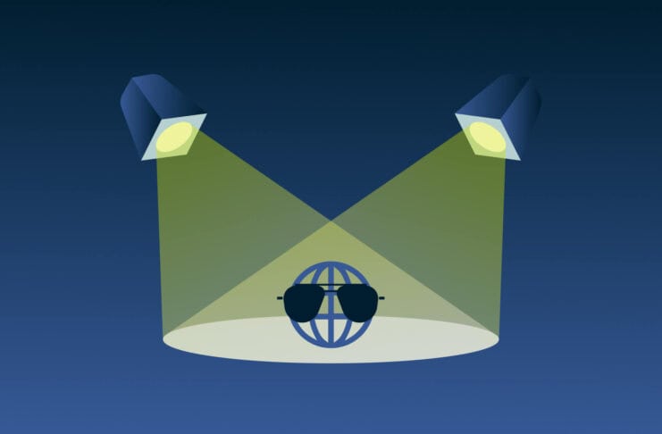 Globe with sunglasses under spotlights.
