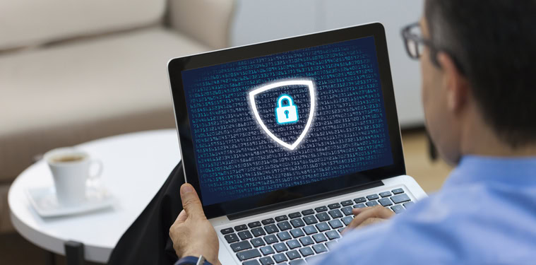 Pessoa usando um notebook que contém um cadeado fechado rodeado de um escudo em sua tela.