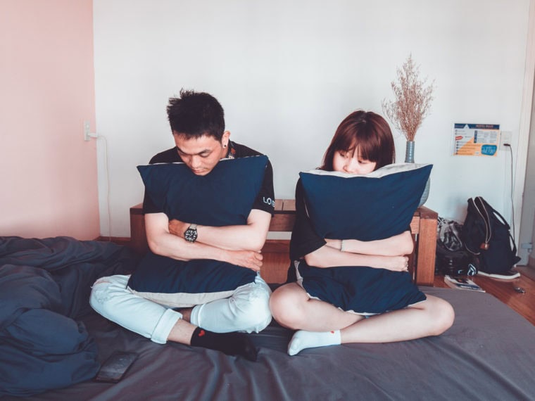 A couple having a fight on a bed.