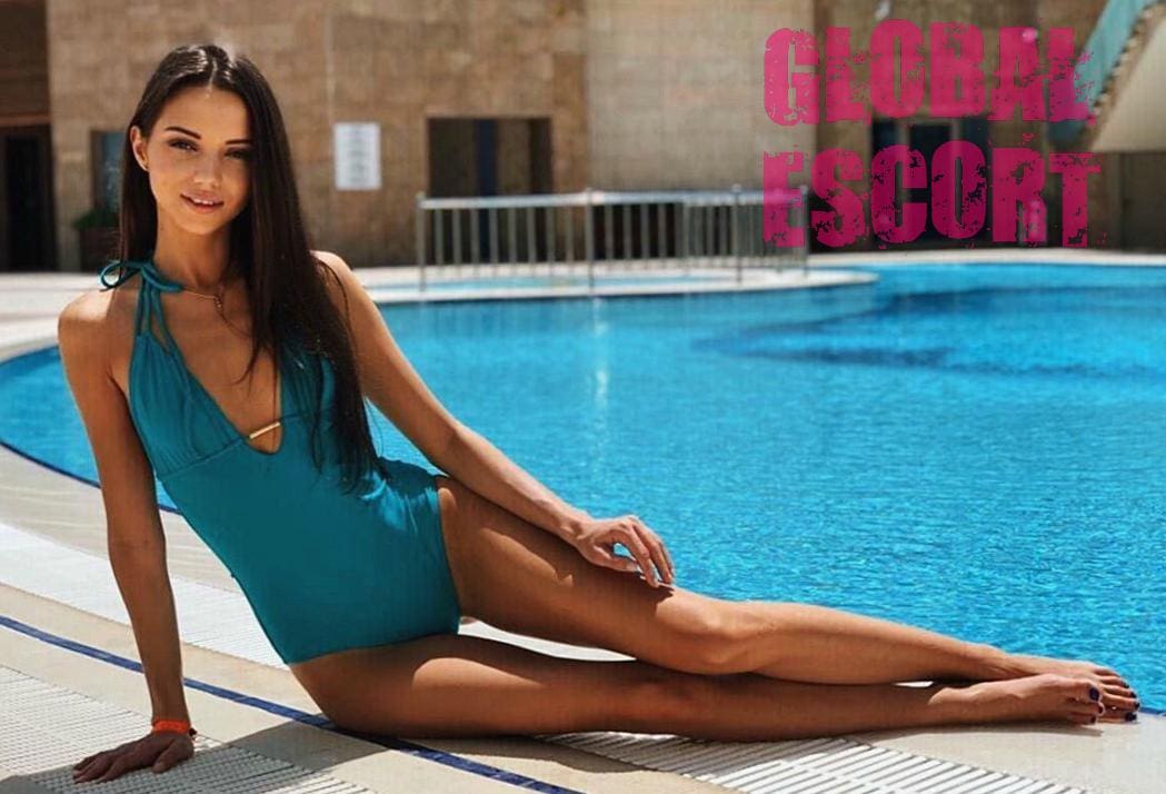 charming escort model in a blue swimsuit lies near the pool
