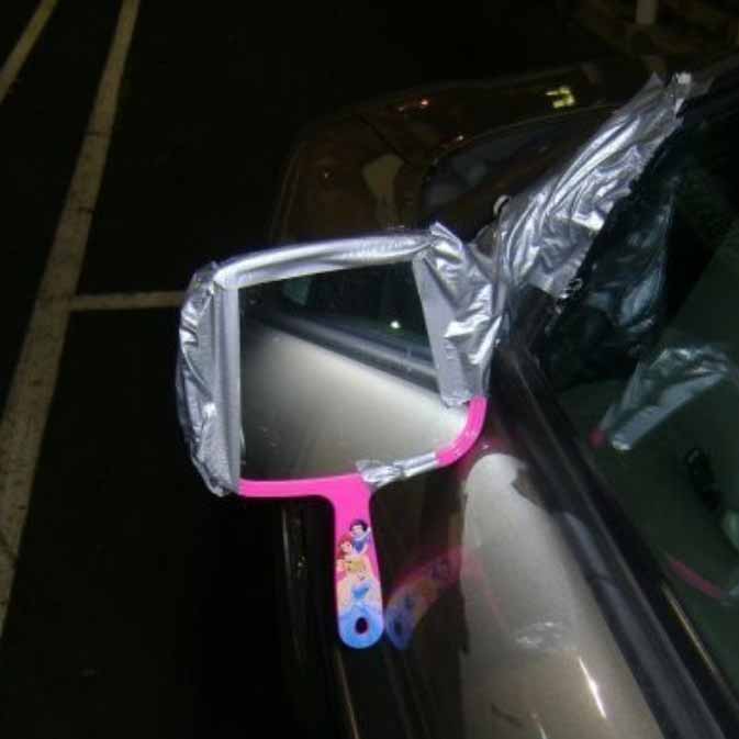 Car with child's toy mirror taped in place of regular mirror