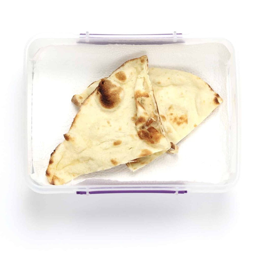 Naan bread in airtight container lined with a paper towel
