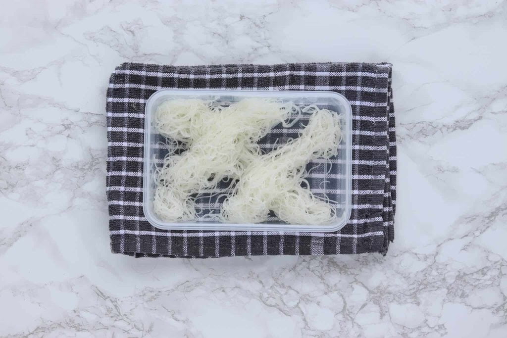 Criss crossed rice noodles in an open Tupperware container.