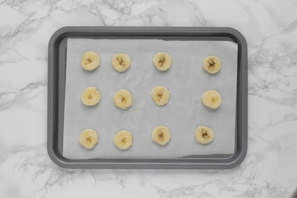 Cut banana slices on a baking tray ready for freezing