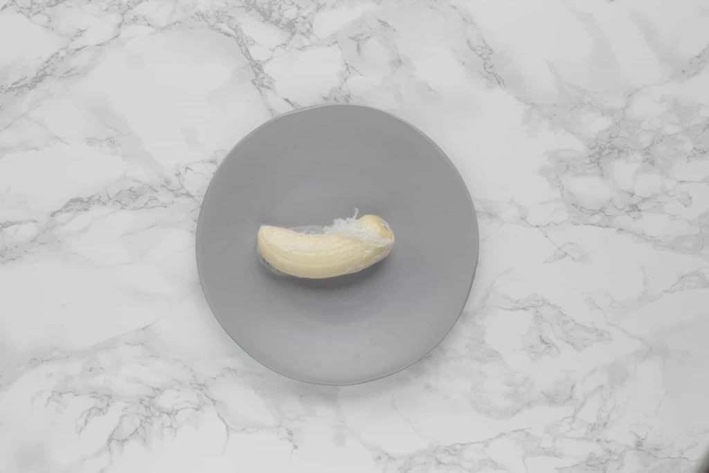 a peeled cut banana wrapped in plastic wrap