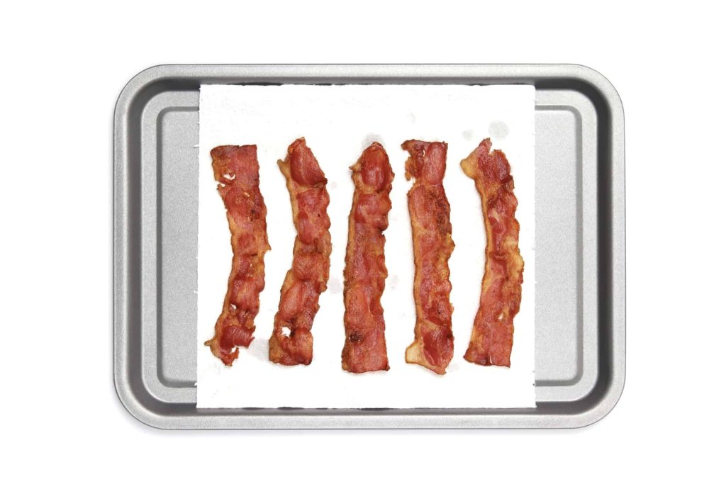 Bacon on a paper towel on a baking tray