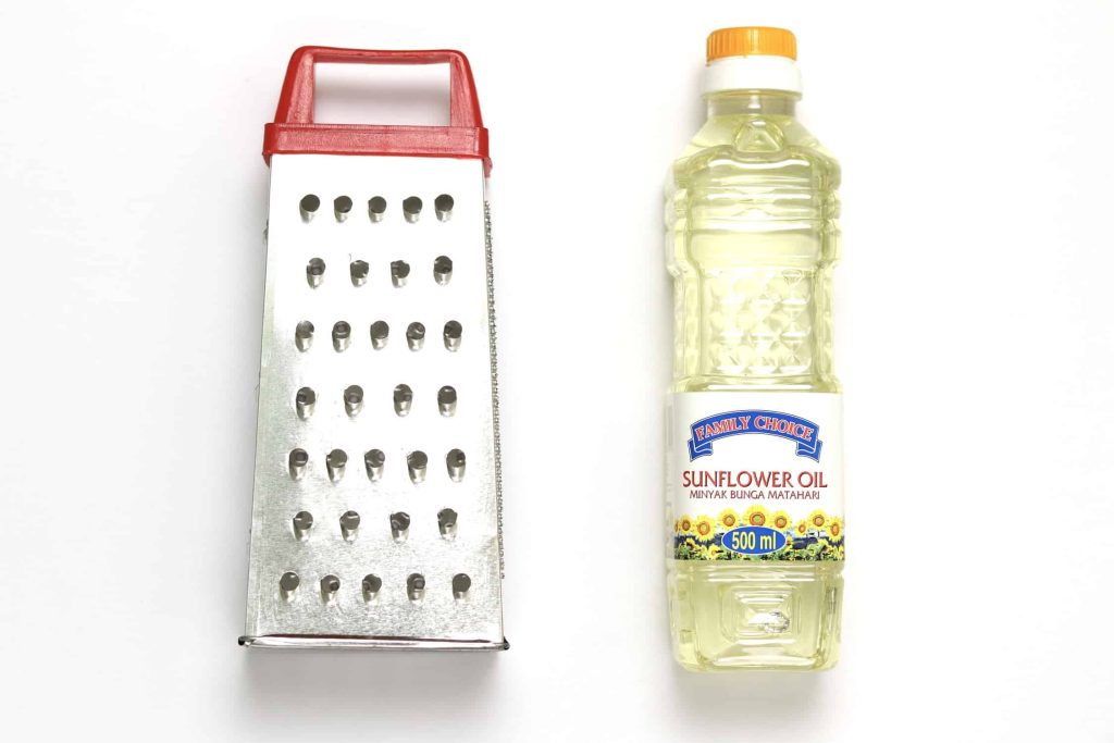A cheese grater lightly coated in sunflower oil, alongside a bottle of sunflower oil.