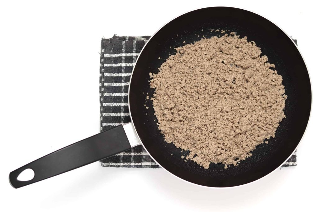 Frying pan filled with powdery ground beef after being cooked and mashed