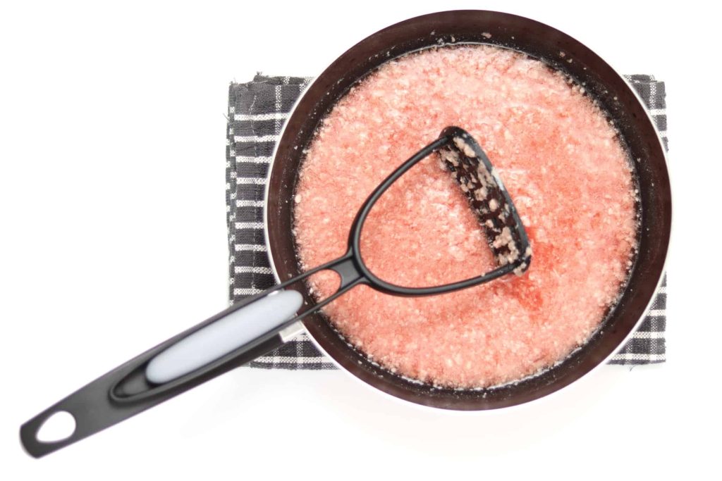 Frying pan filled with cold water and a slurry of mashed, uncooked ground beef