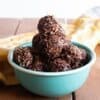 chocolate coconut macaroons in a turquoise bowl on a wooden surface, with a yellow napkin behind.