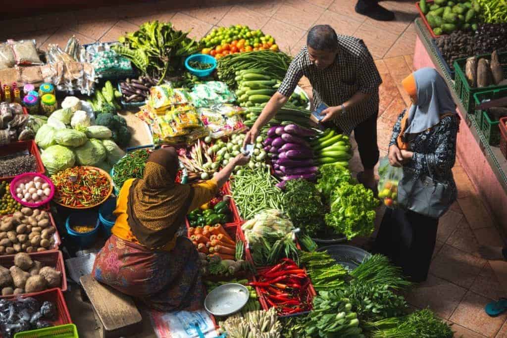 People at a market buying vegetables