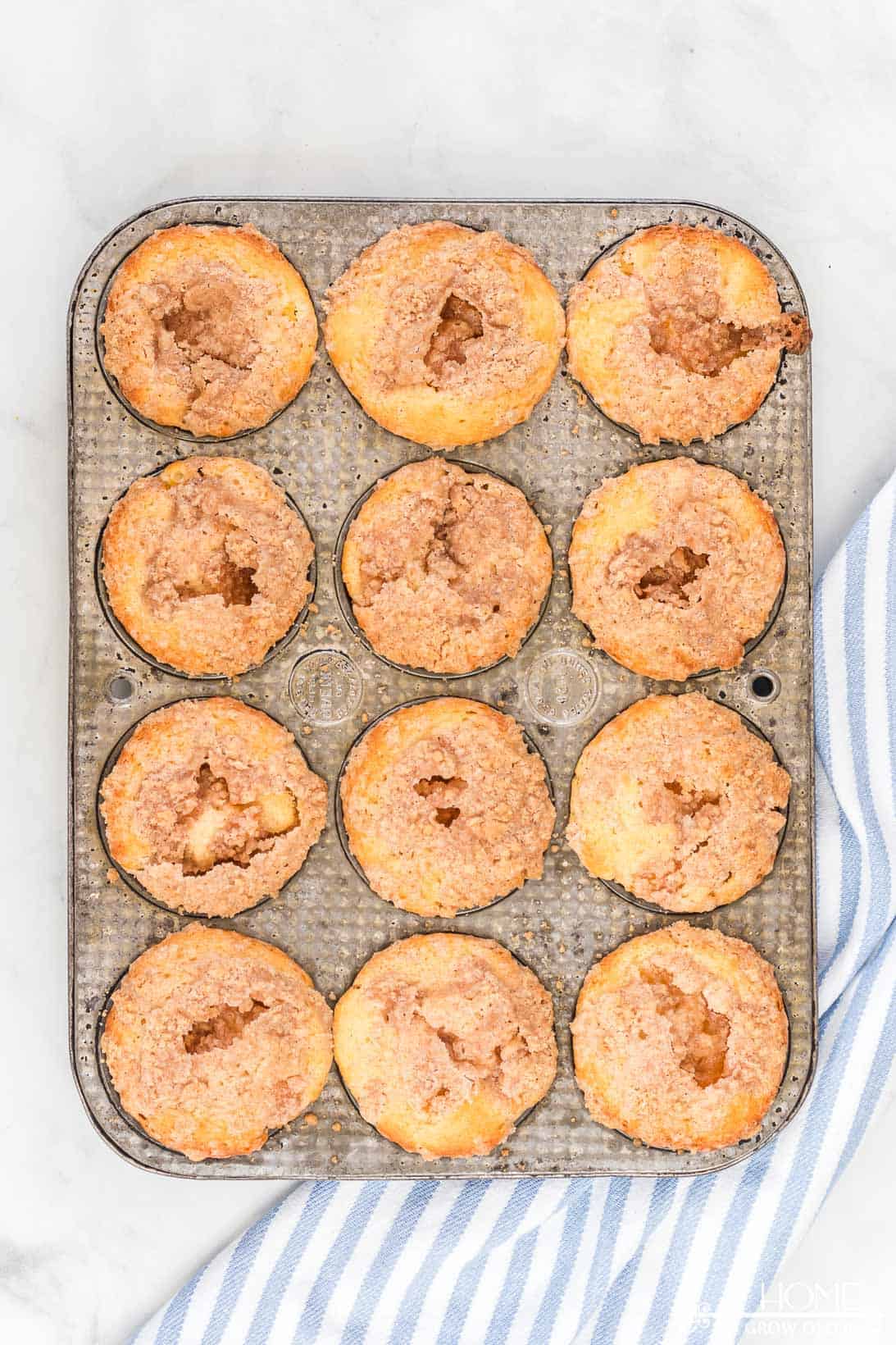 freshly baked peach cobbler muffins still in a muffin tin