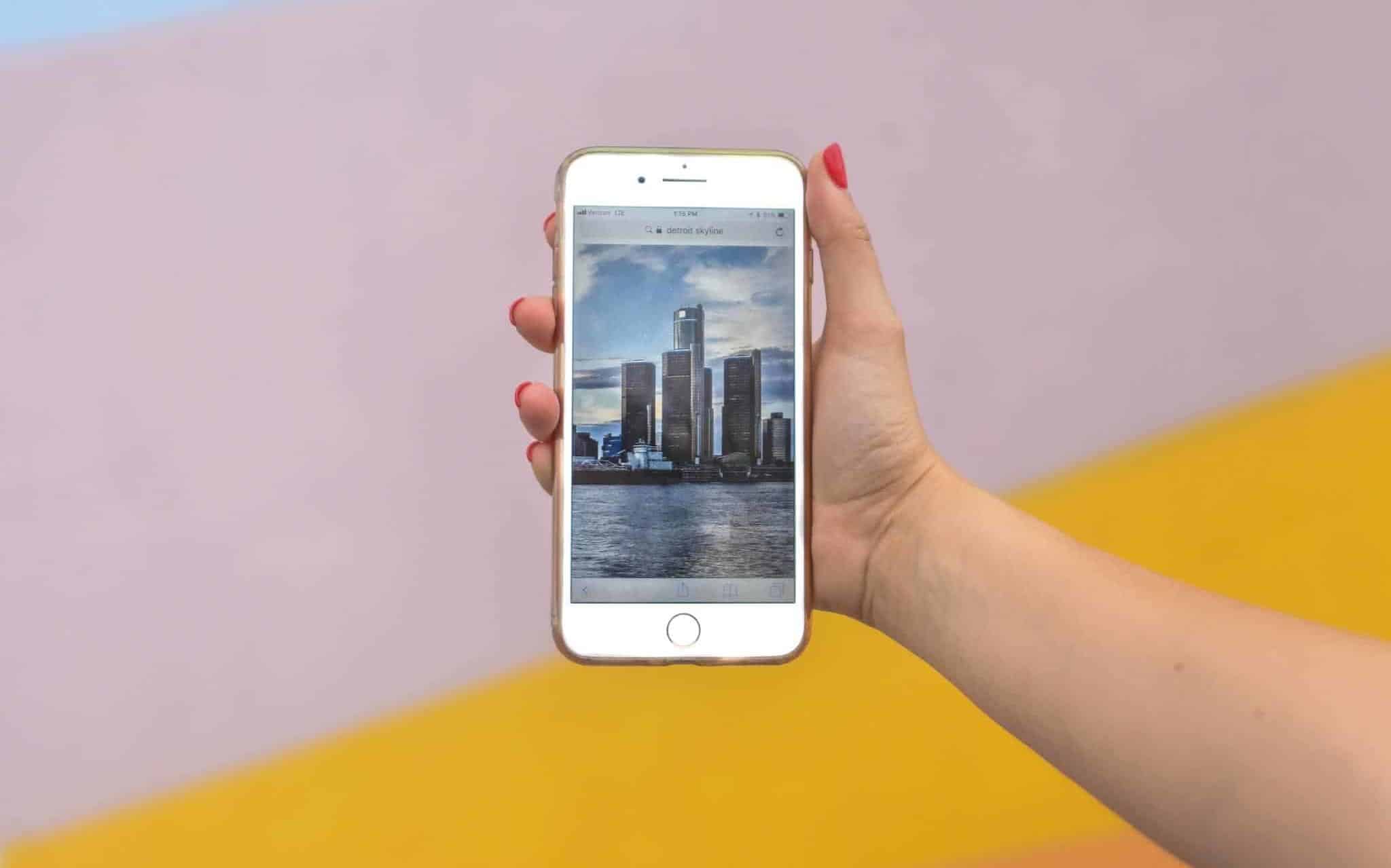 A person holding a phone in front of a colorful background.