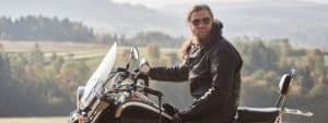 bearded motorcyclist man with long hair in black leather jacket