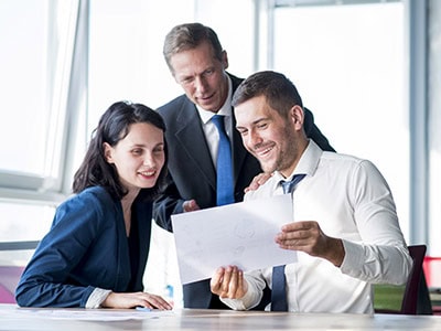 Three business people looking at paper and smiling