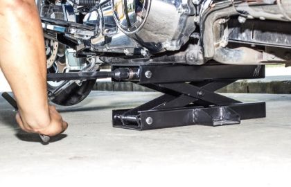 hand using a jack to repair motorycle