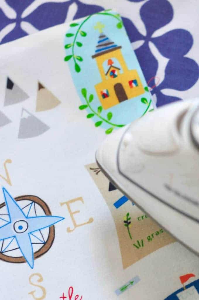 Adventure themed fabric is shown being pressed by an iron to make seams crisp.