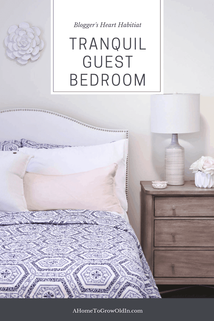 white upholstered bed with blue and white patterned quilt and wood nightstand with lamp