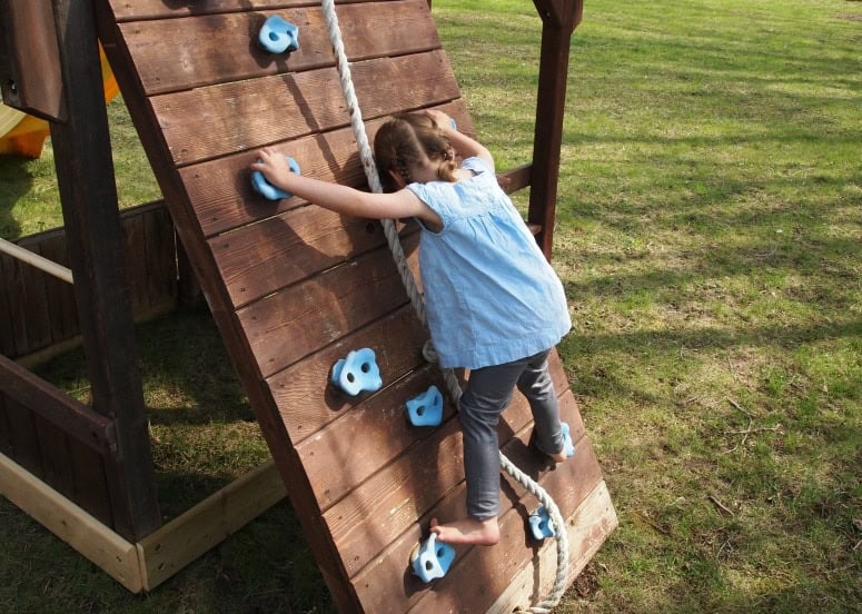 barefoot child climbing on a playground outside