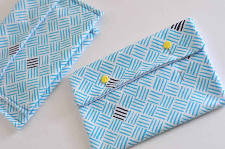 Blue patterened snack bags are laid out on a white surface. The main bag is shown with the bottom and top pinned in place, ready for the final closing seams to be sewn.