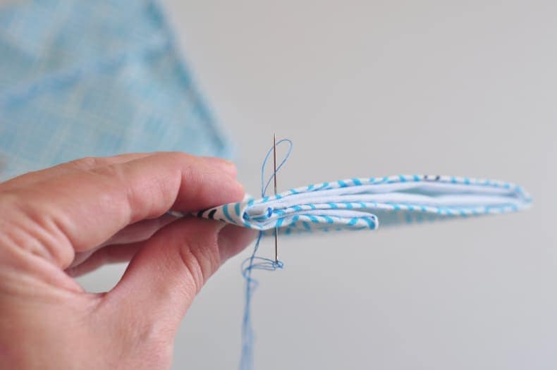 The closing side seam of a snack bag is shown with a needle passing through the six layers of fabric to demonstrate a technique for tidy seam closing.