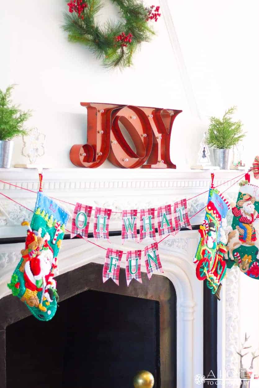 Oh What Fun DIY fabric Christmas banner hanging from a fireplace mantle with Christmas stockings