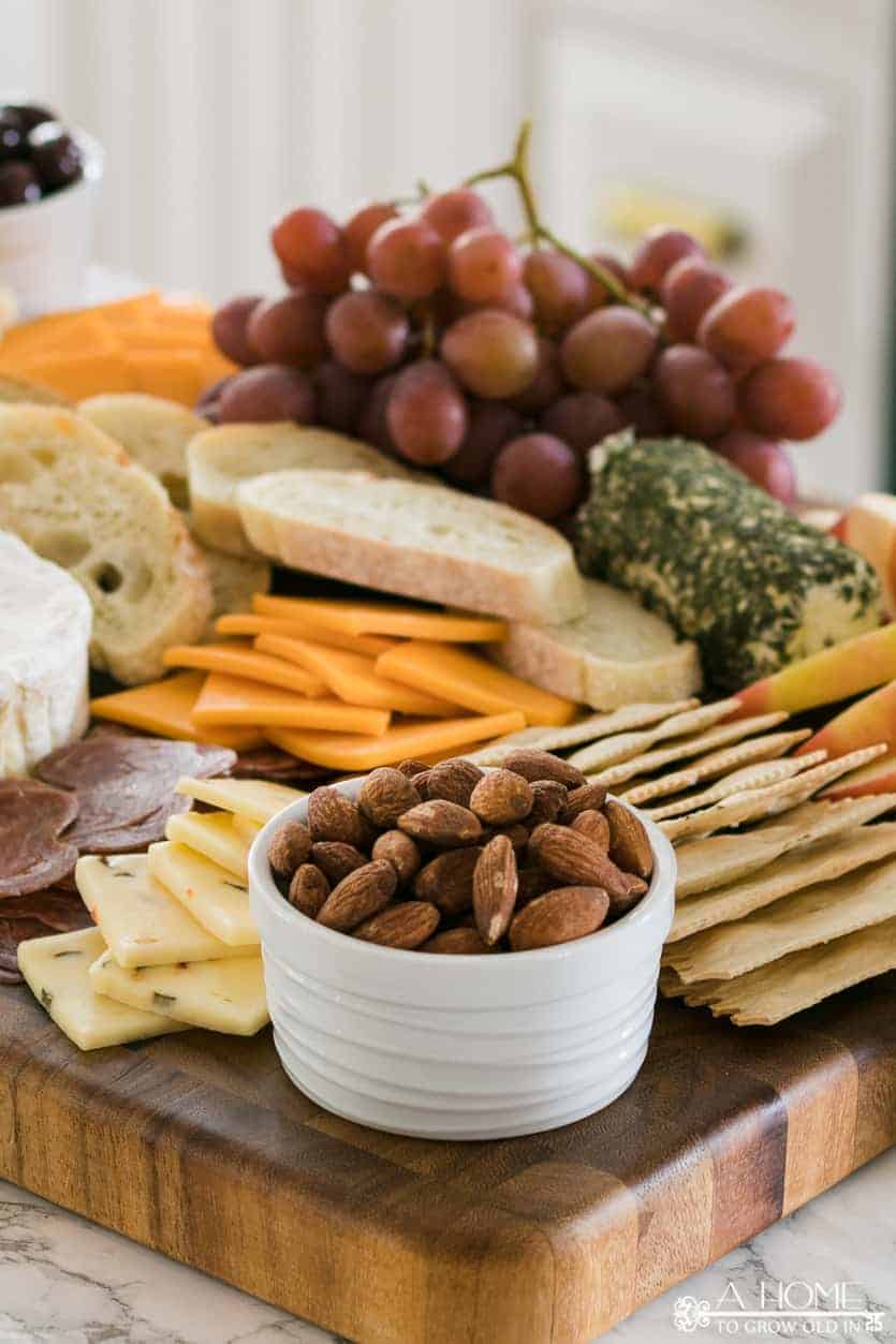 bowl of almonds surrounded by cheese and crackers on a cheeseboard