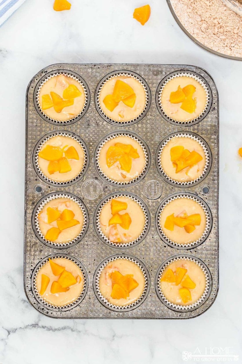 peach cobbler muffins batter added to muffin tin