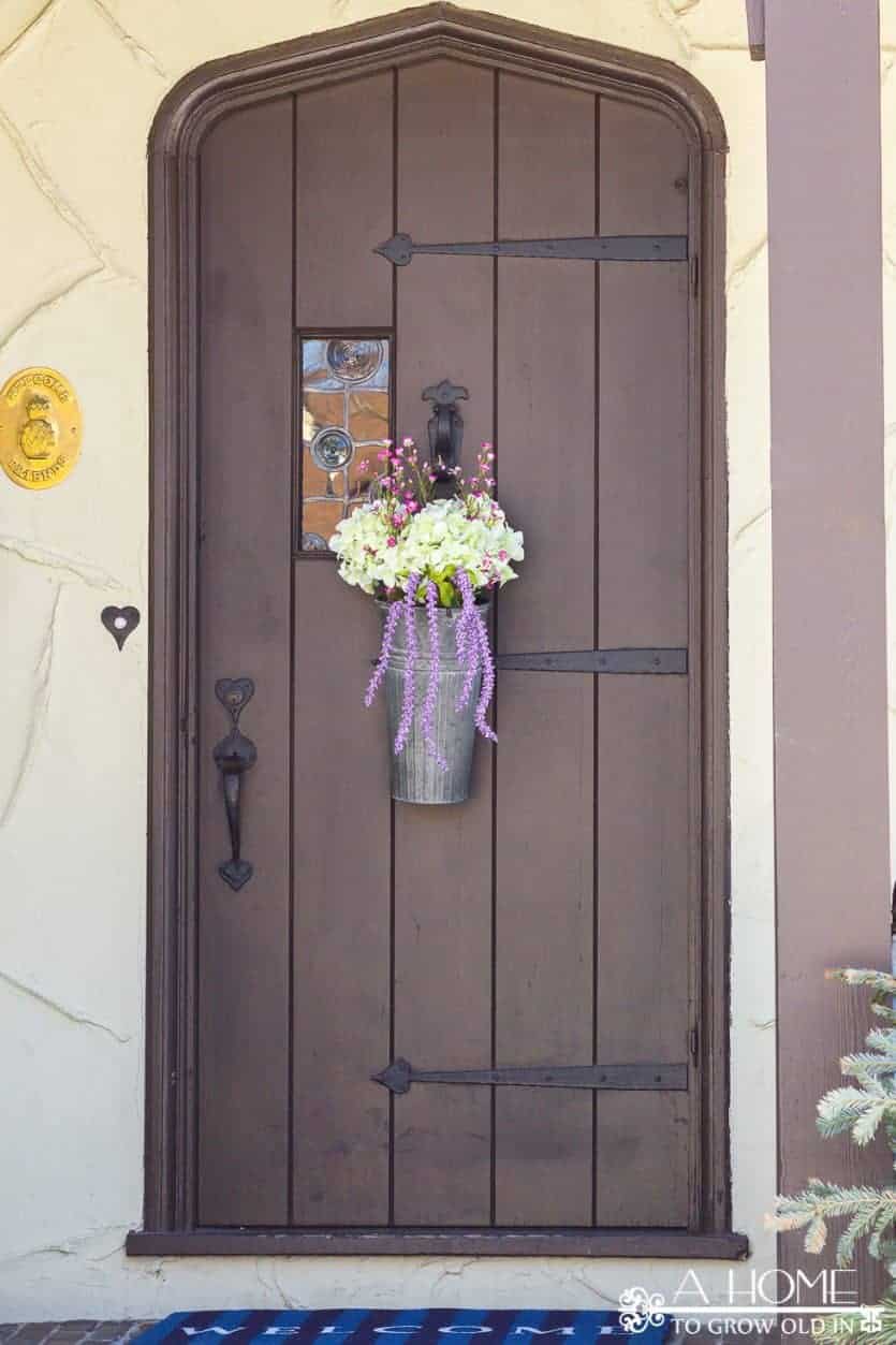 This spring floral door hanger is so easy to do and requires no floral arranging skills! A flower arrangement is a fun alternative to a wreath! Plus, I love the galvanized bucket!