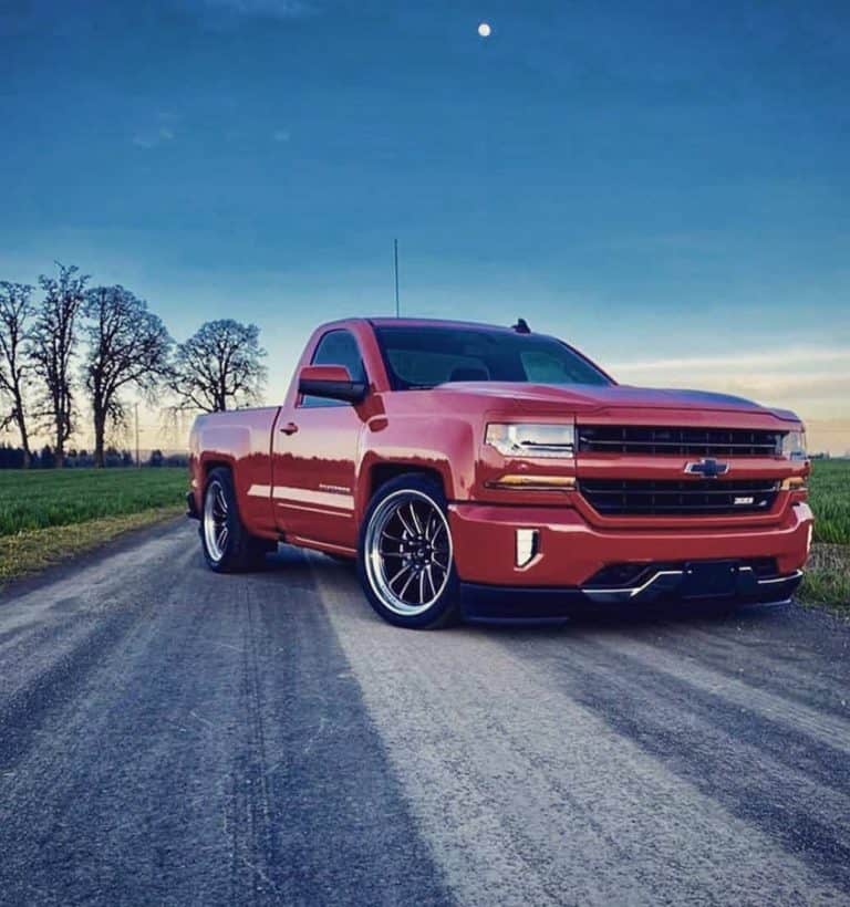 red chevy silverado with shocks and building background