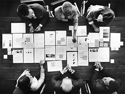 Aerial view of six employees in a business meeting to compare landline service to VoIP service