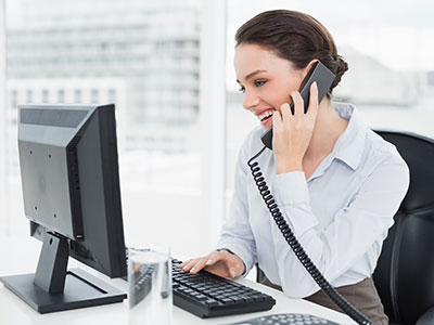 Business woman smiling on phone, happy to learn she can replace commercial landlines with a VoIP phone system