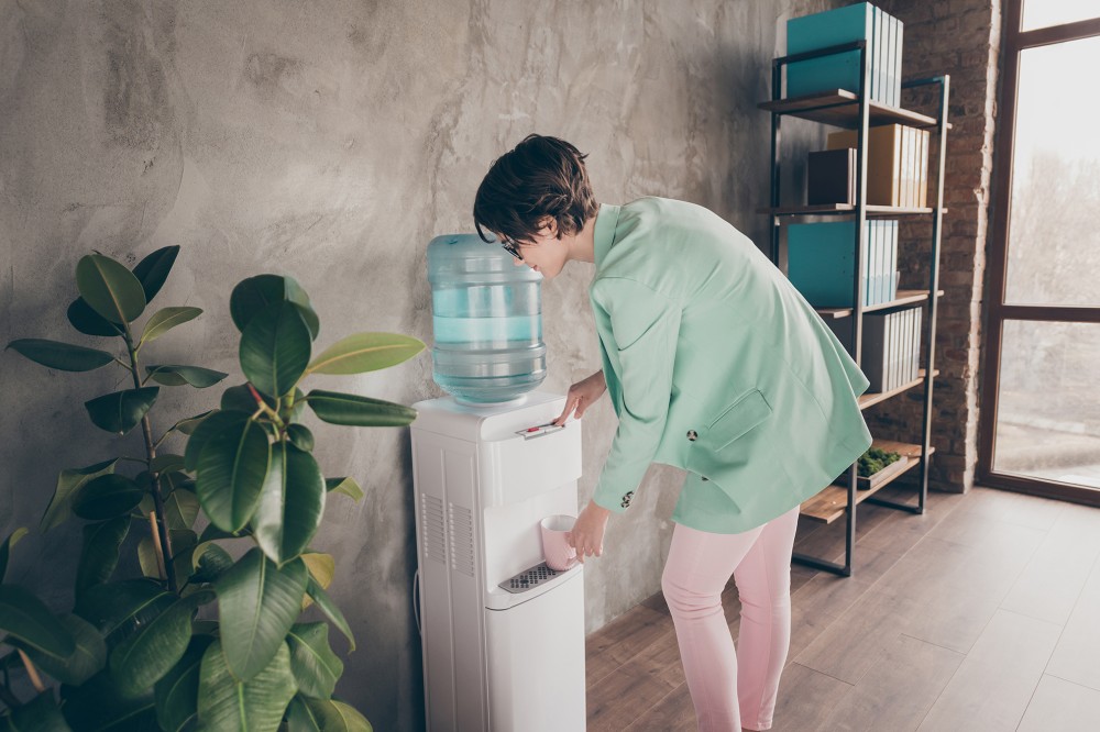 Woman using water cooler in reception area