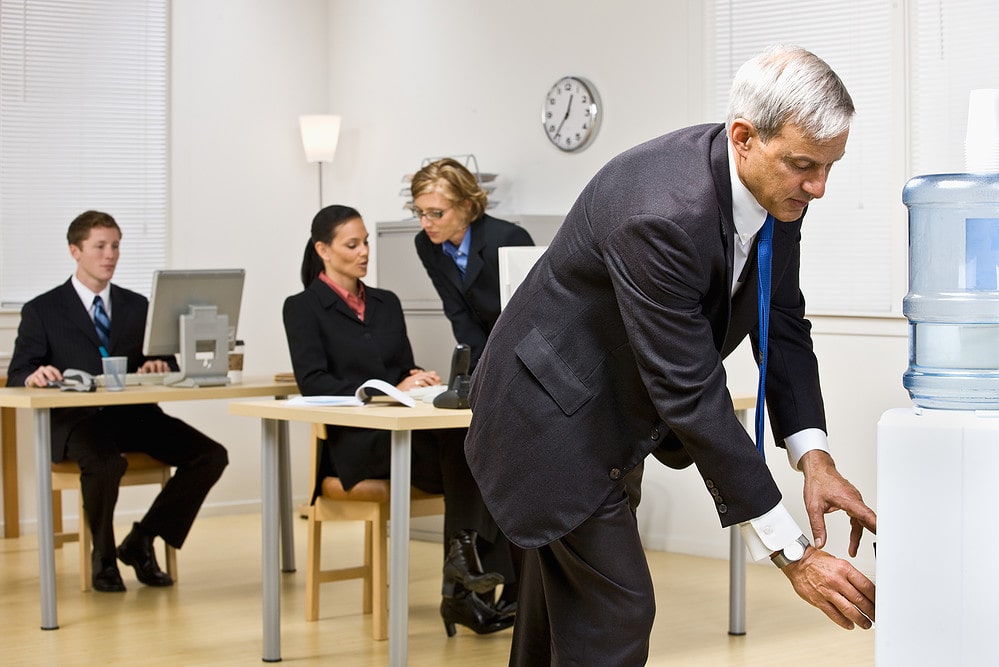 Employee using water dispenser in staff kitchen
