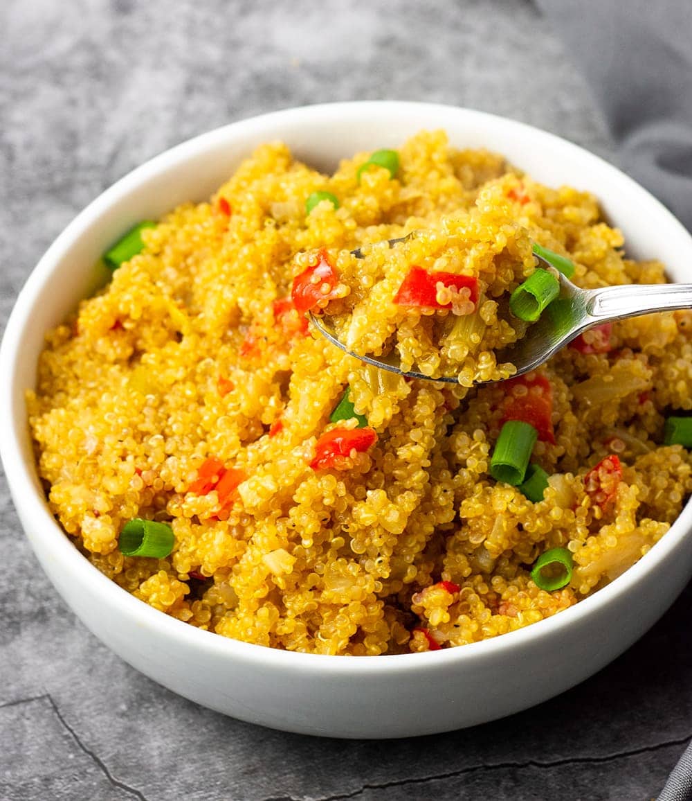 quinoa pilaf cajun style in a white bowl on a grey backgroun
