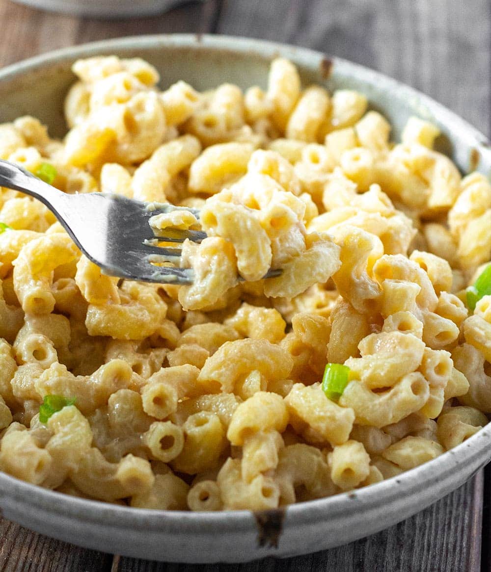 Vegan Mac And Cheese without nuts in a beige bowl with a silver fork
