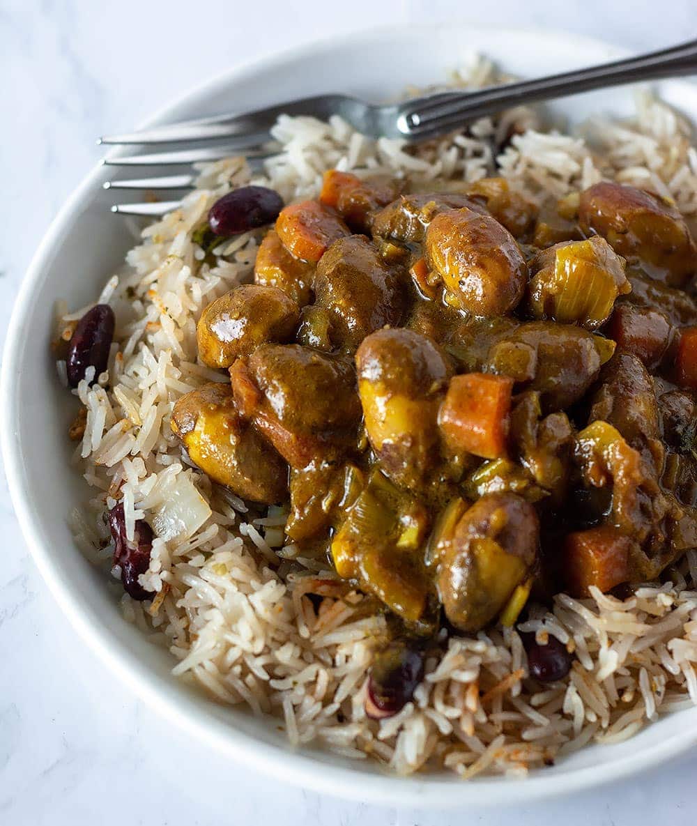 Jackfruit seed curry on a bed of rice and peas in a white plate with a fork