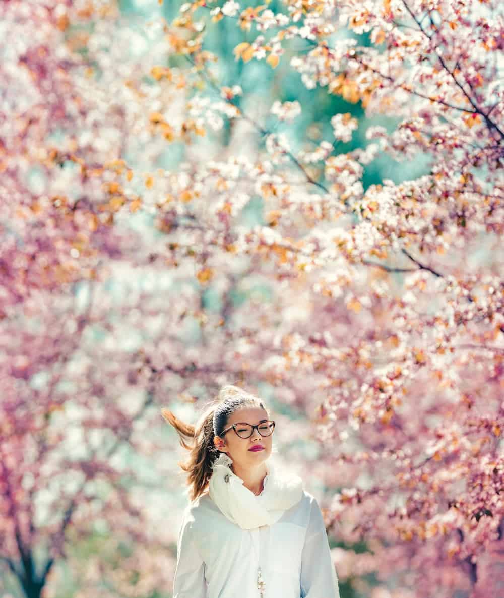 Being an empath, woman walks among the cherry blossoms.
